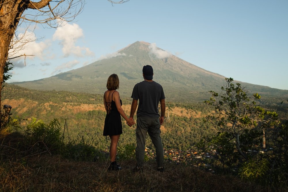 Couple,Holding,Hands,With,View,Of,Mount,Agung,At,Sunrise.