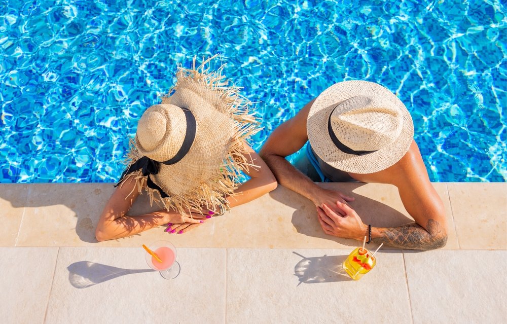 Couple,Enjoying,Drinks,By,The,Pool,,Overhead,View