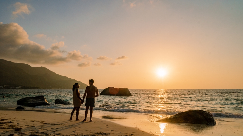 Couple watching a romantic beach sunset, a perfect start or end to a 2-week Africa honeymoon itinerary