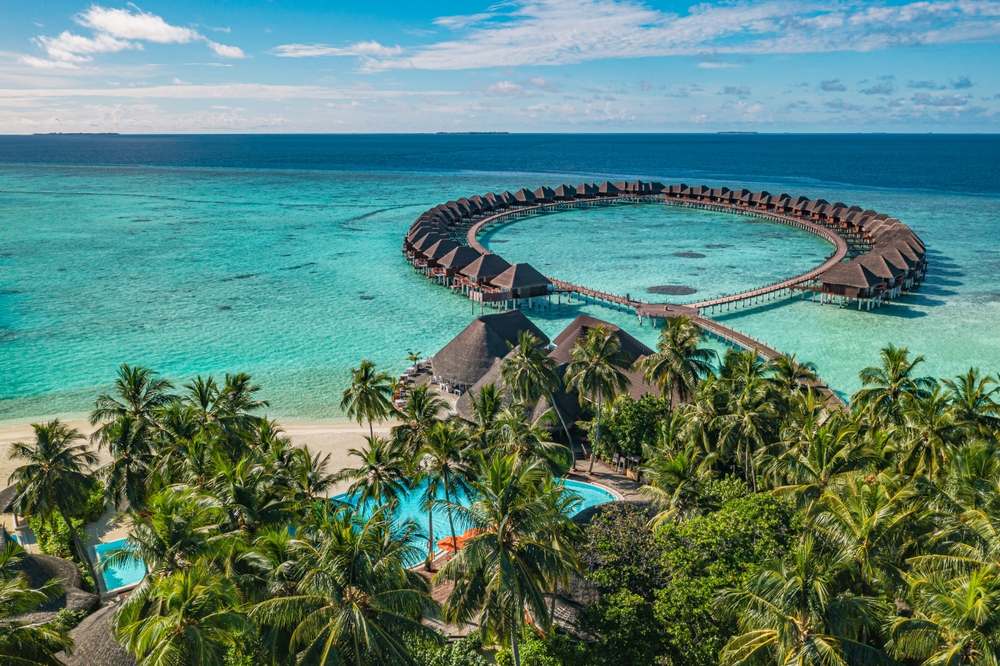 Aerial view showing the comparison of an overwater villa or beach villa maldives, with circular water bungalows and island beachfront accommodation. 
