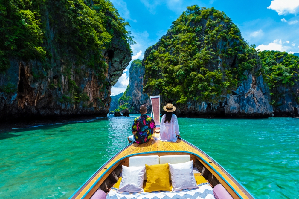 Couple relaxing on a traditional longtail boat in Krabi during an affordable Thailand honeymoon