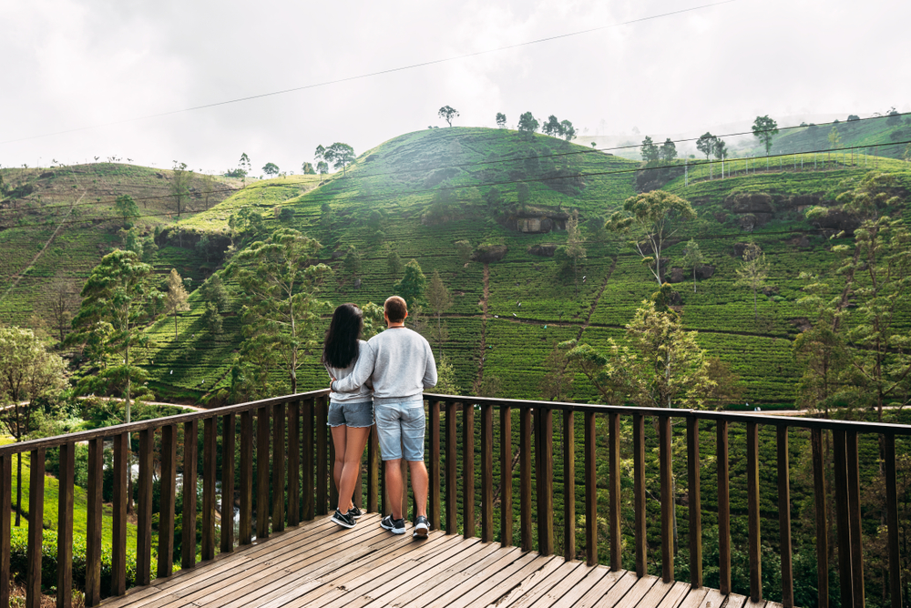 Couple enjoying misty tea plantation views from balcony at the best honeymoon hotels in Nuwara Eliya