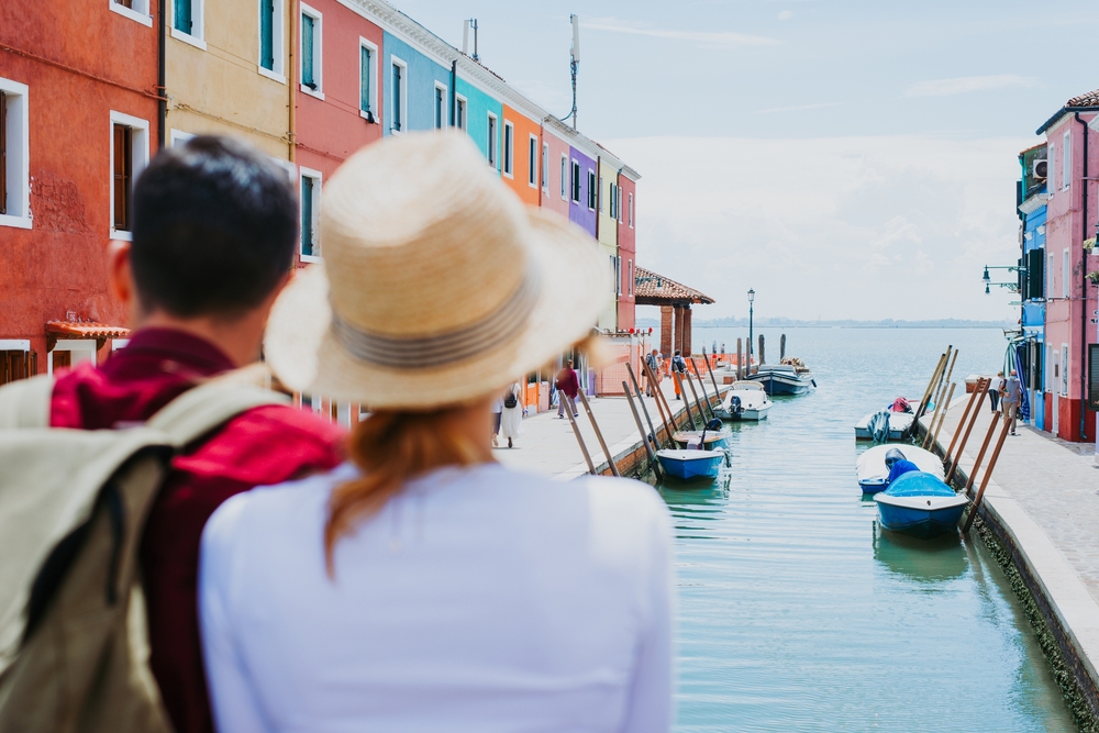 Romantic couple exploring colorful canals during their Venice Italy honeymoons trip.
