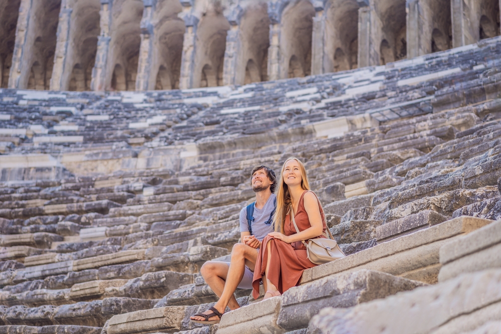 Couple sitting on the stone steps of an ancient amphitheater while sightseeing on their Turkey honeymoon.