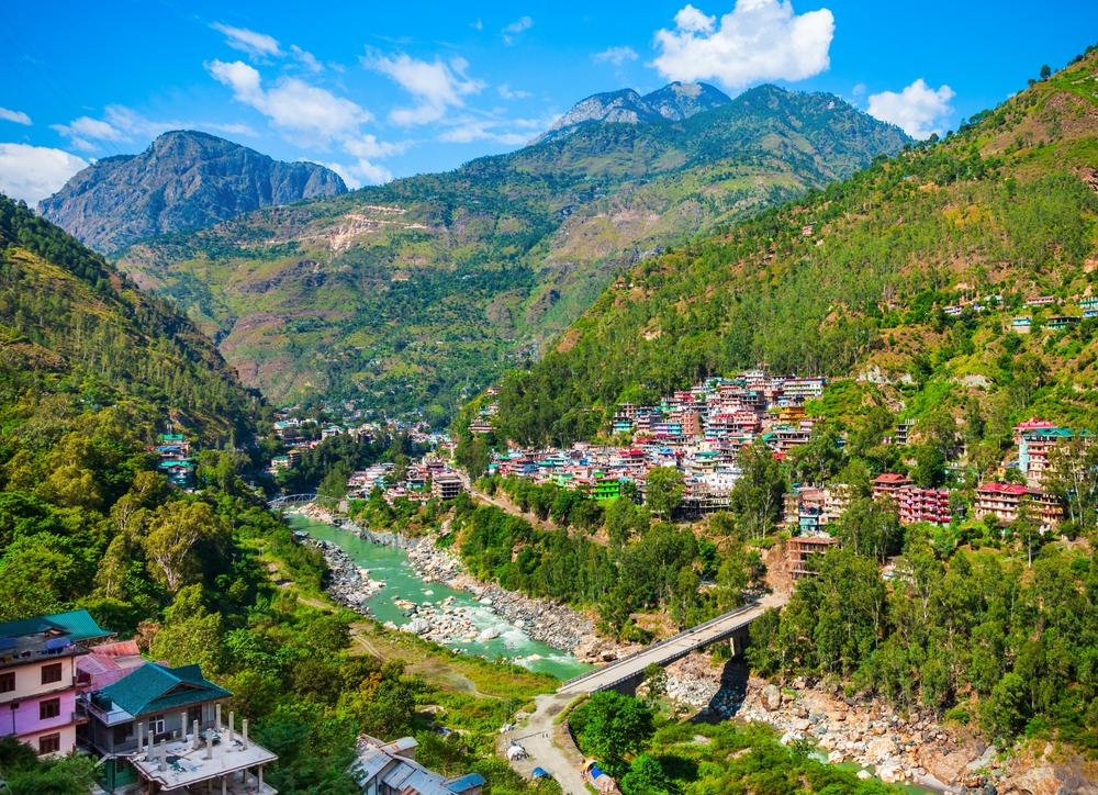 Panoramic view of a river flowing through lush green mountains near romantic Shimla honeymoon places.