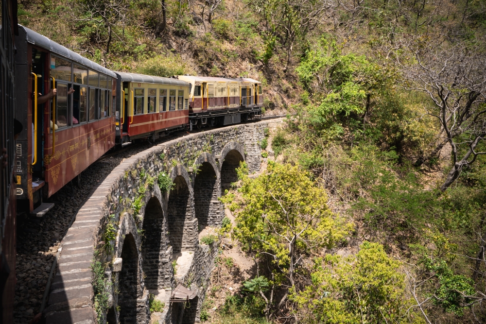 Scenic Kalka Shimla Toy Train ride crossing a stone arch bridge, one of the top romantic Shimla honeymoon places.