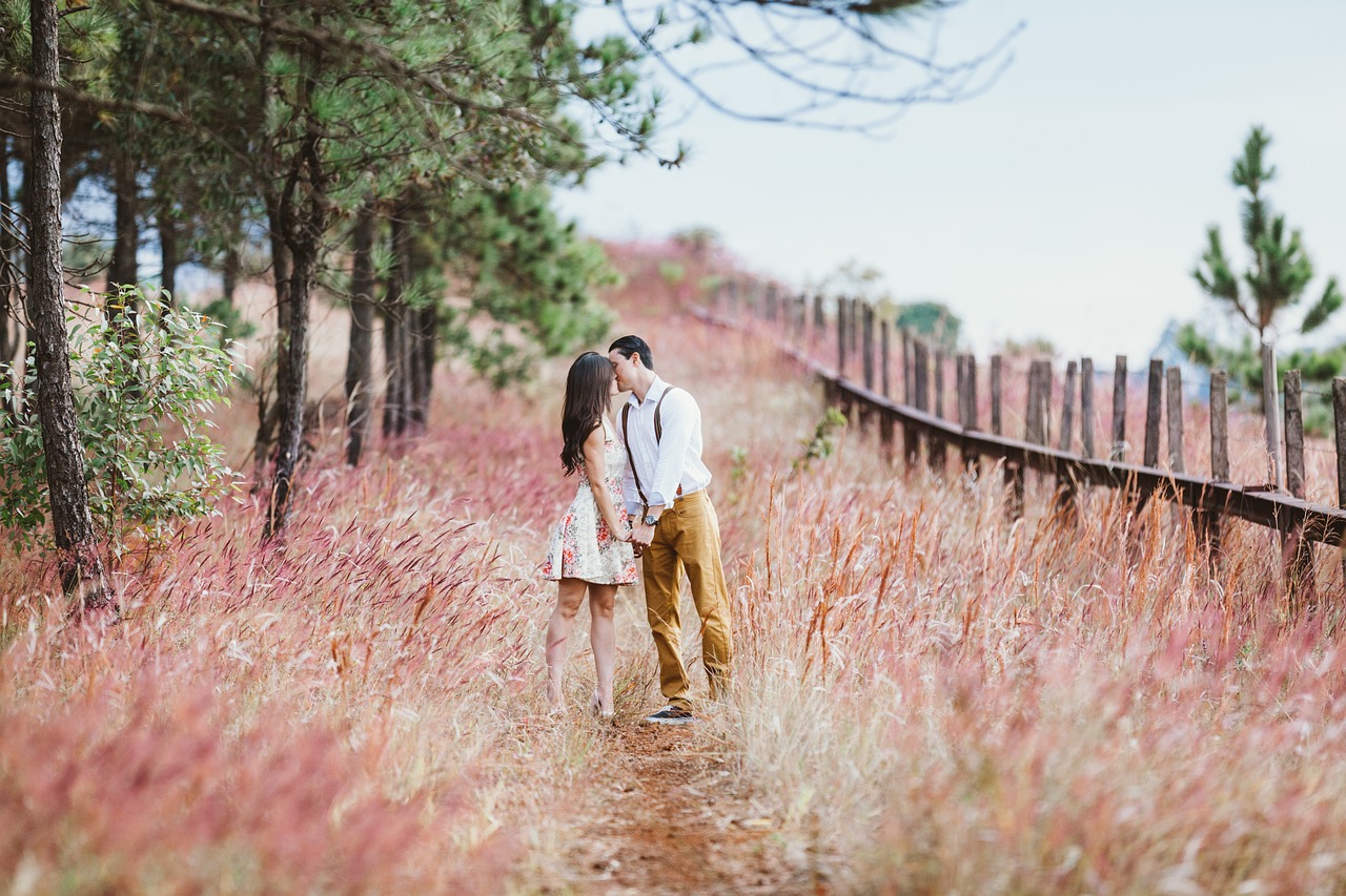 Romantic couple kissing in a scenic field of pink grass and pine trees during their Tokyo honeymoon photoshoot