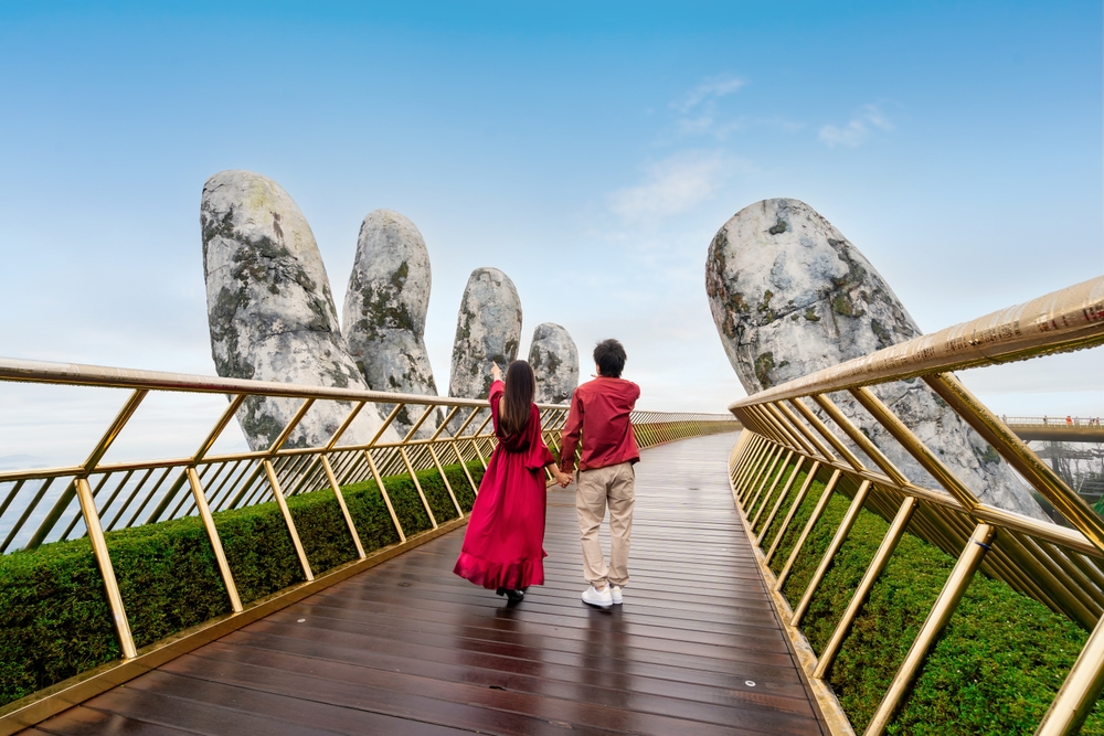 Couple holding hands on the Golden Bridge in Da Nang during a romantic Vietnam honeymoon   