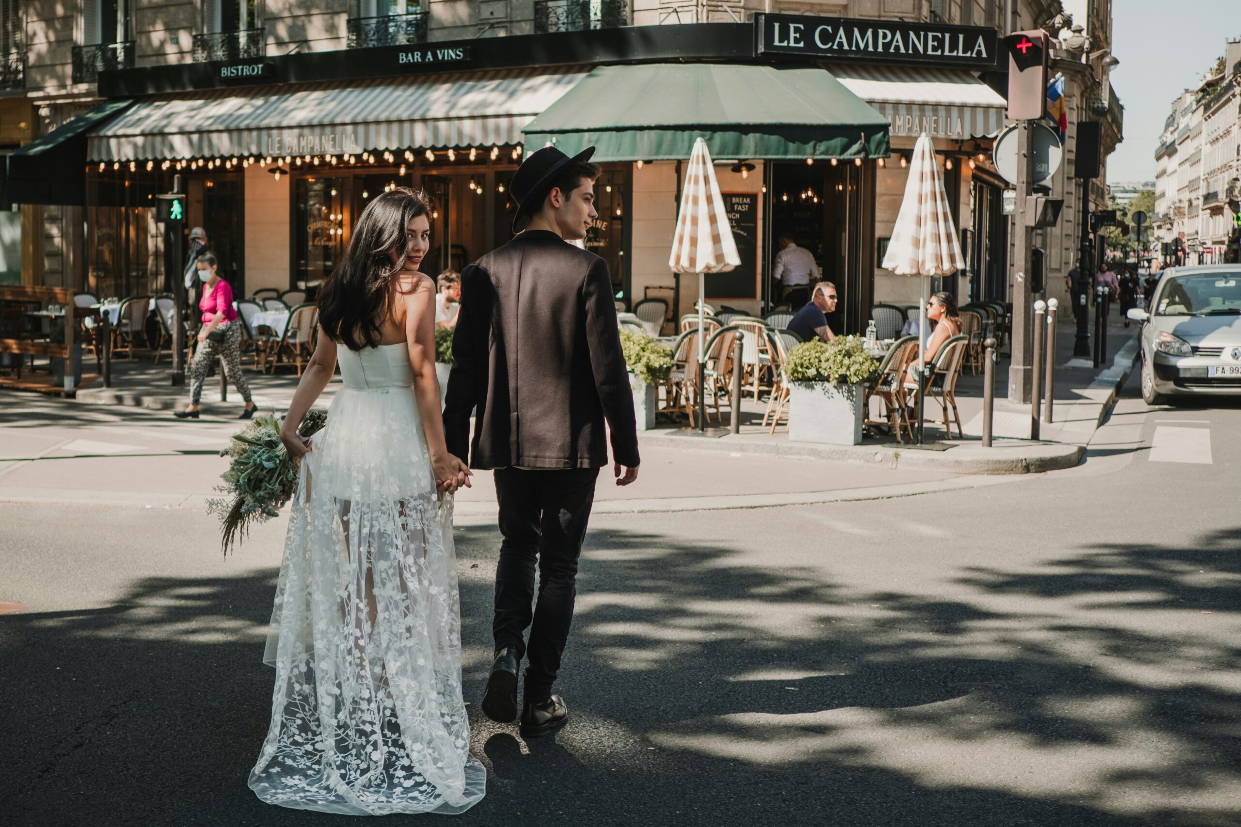 A romantic couple holding hands and walking past a classic cafe, exploring the city near the most romantic places to stay in Paris