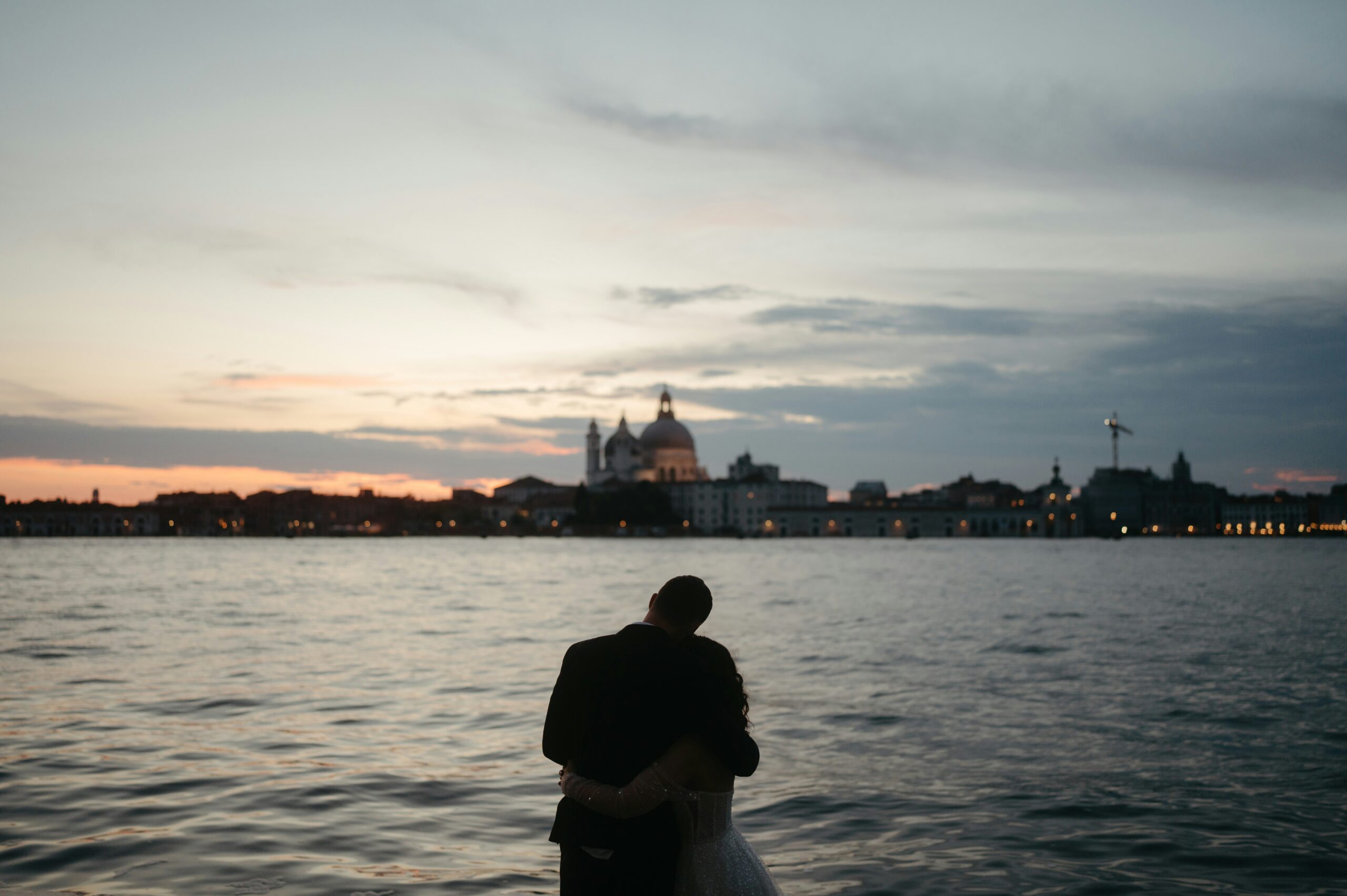 Newlywed couple embracing during a romantic sunset in Venice, a highlight of premium Italy honeymoon packages 2026