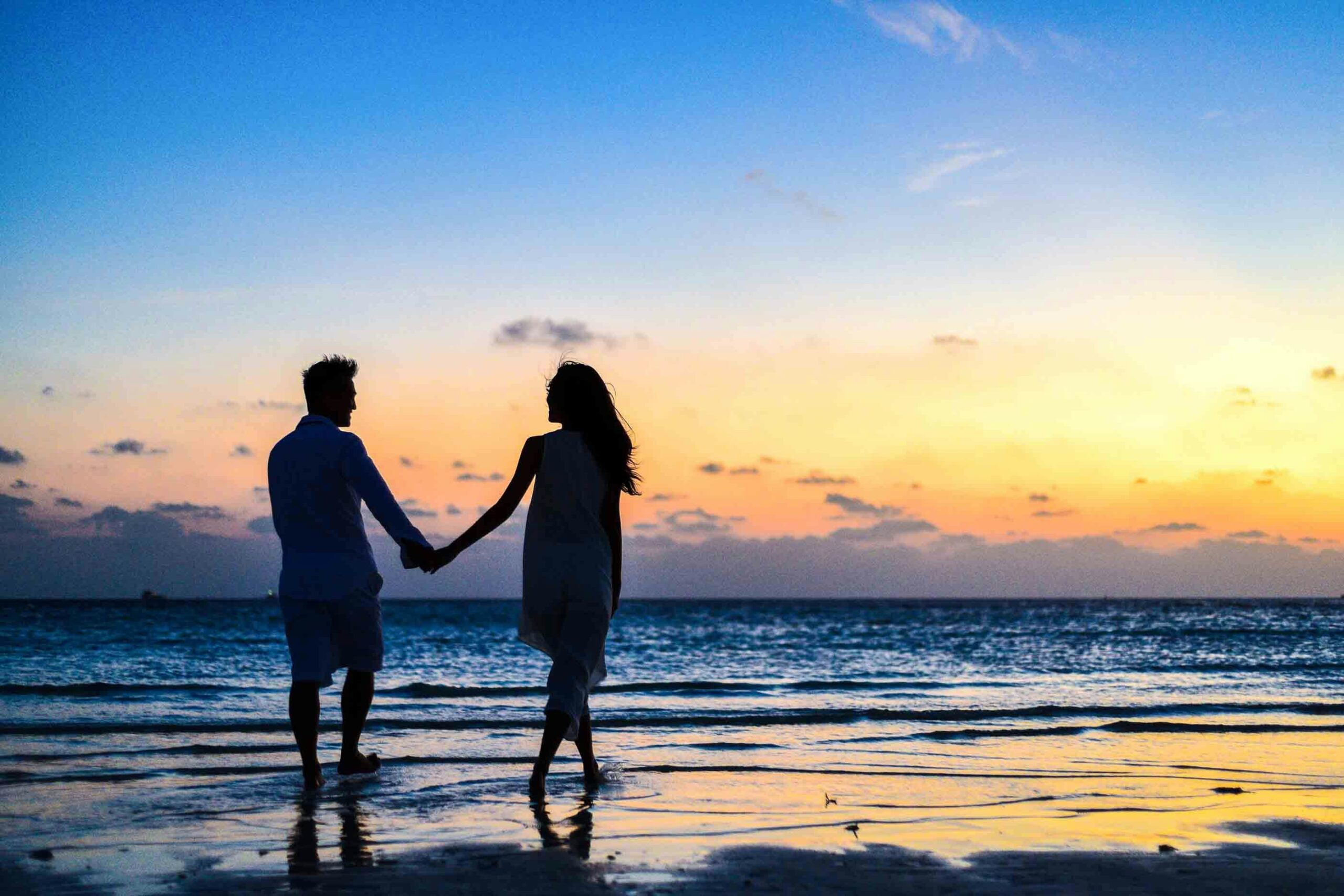 A romantic couple enjoying the sunset on a beach, representing the beauty of an India honeymoon.