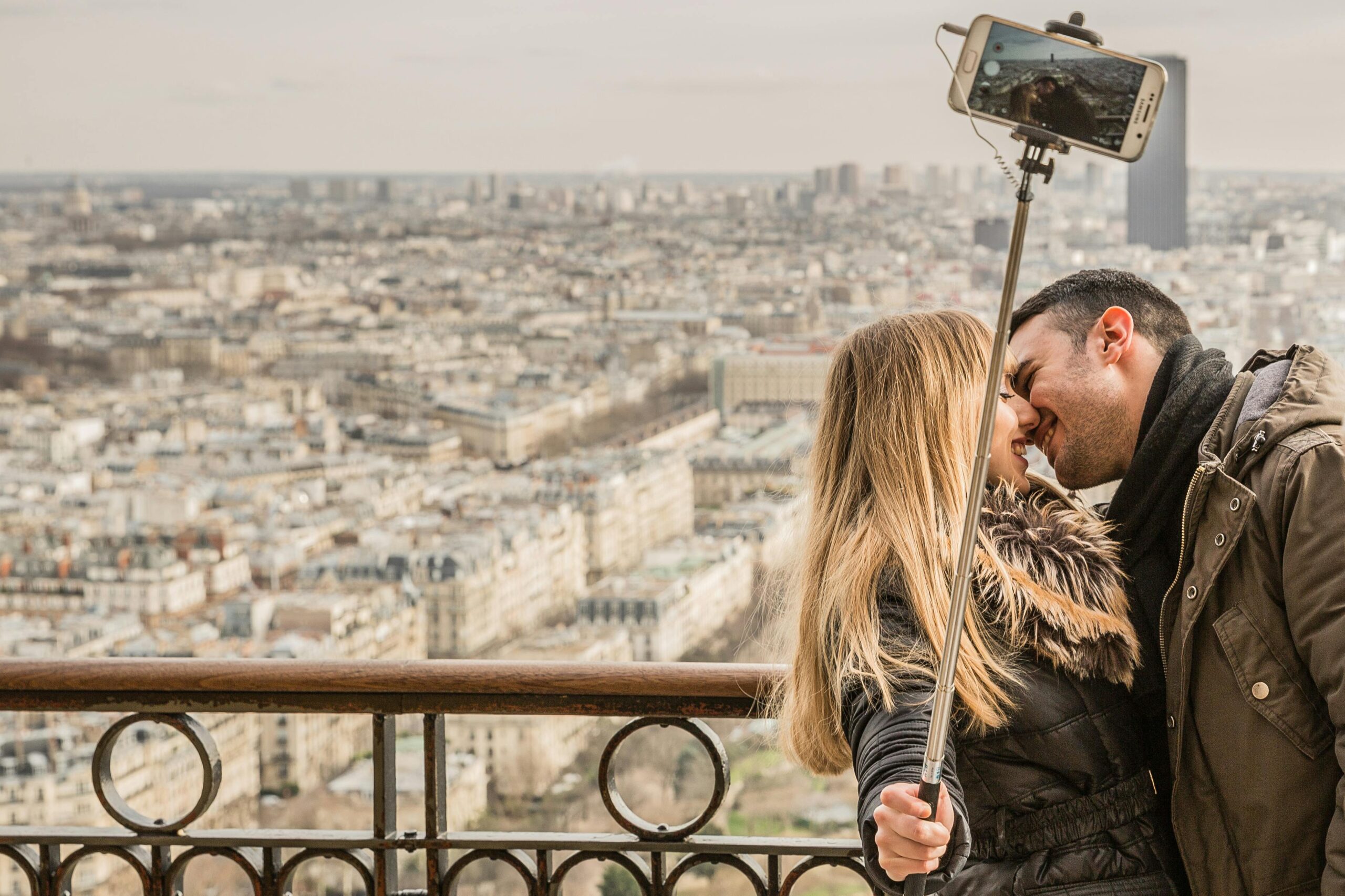 A romantic honeymoon couple taking a selfie with a high-angle view of Paris rooftops from secret hotels in paris locals love