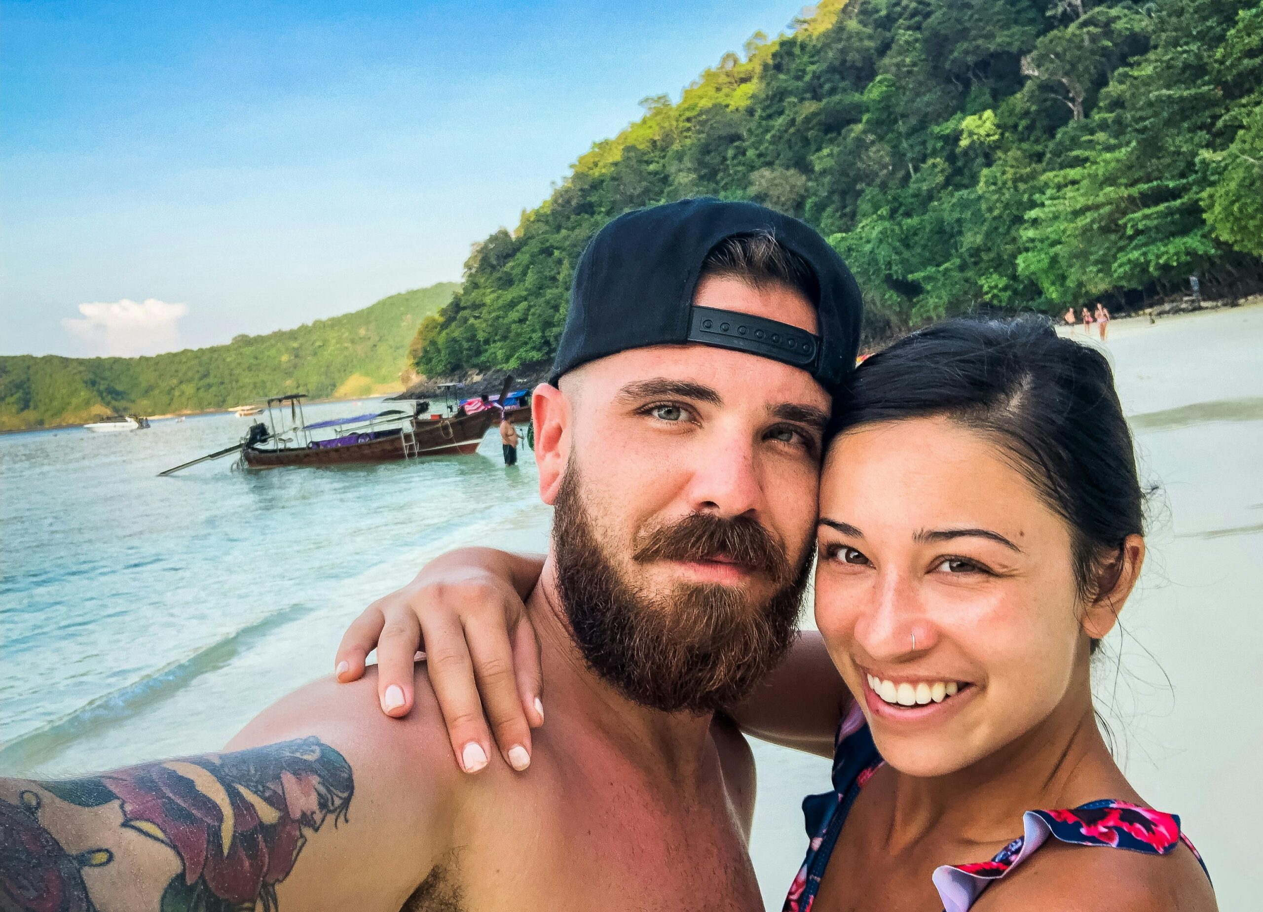 A happy newlywed couple taking a selfie on a sunny beach enjoying Thailand honeymoon places
