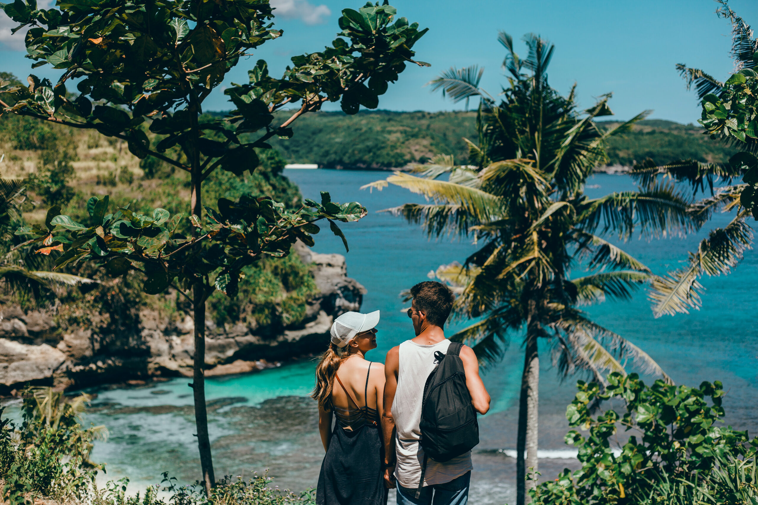 A romantic couple enjoying a tropical beach honeymoon in Sri Lanka, standing together and looking at the turquoise sea surrounded by lush greenery during their honeymoon in Sri Lanka.
