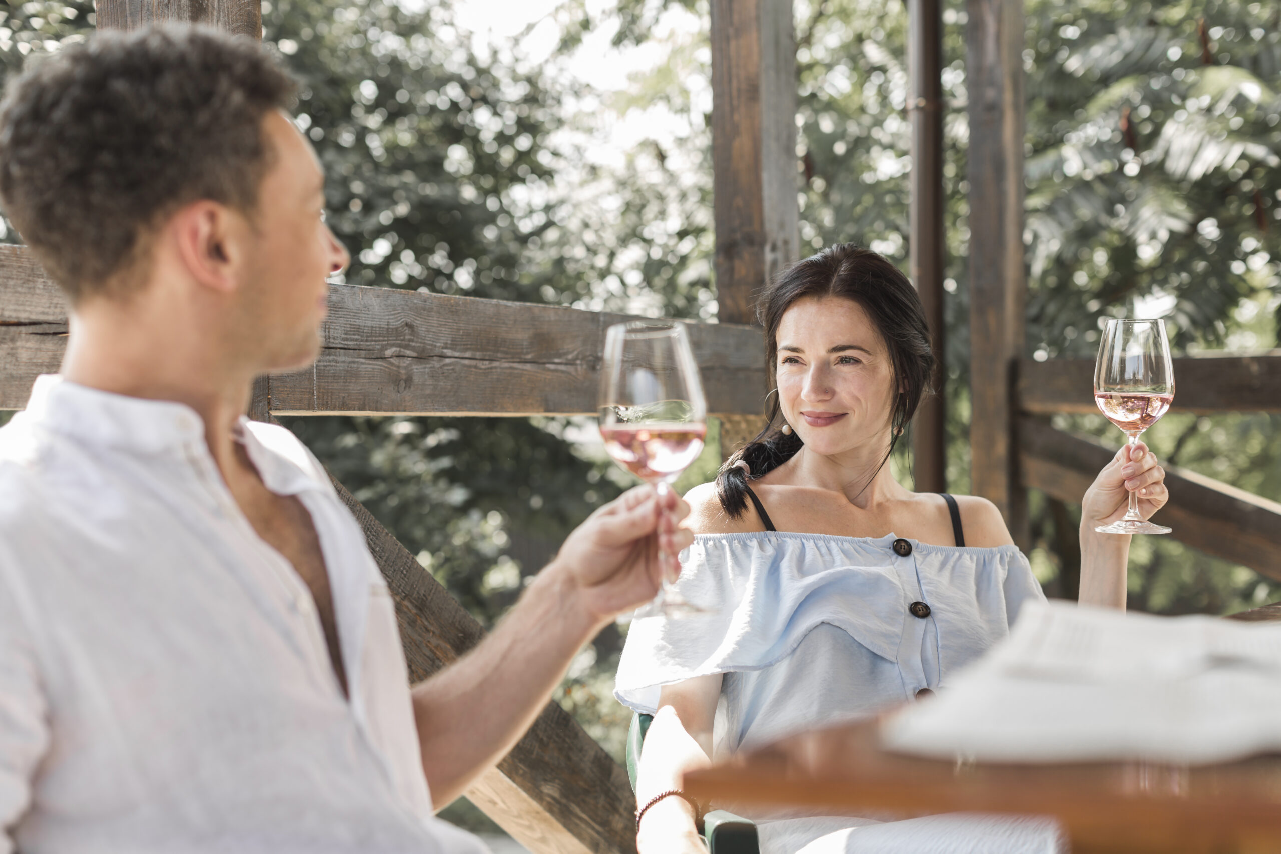 Romantic couple enjoying wine on a wooden deck during their luxury African safari honeymoon